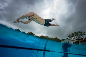 Competitive swimmer diving from the starting block photographed from water level.