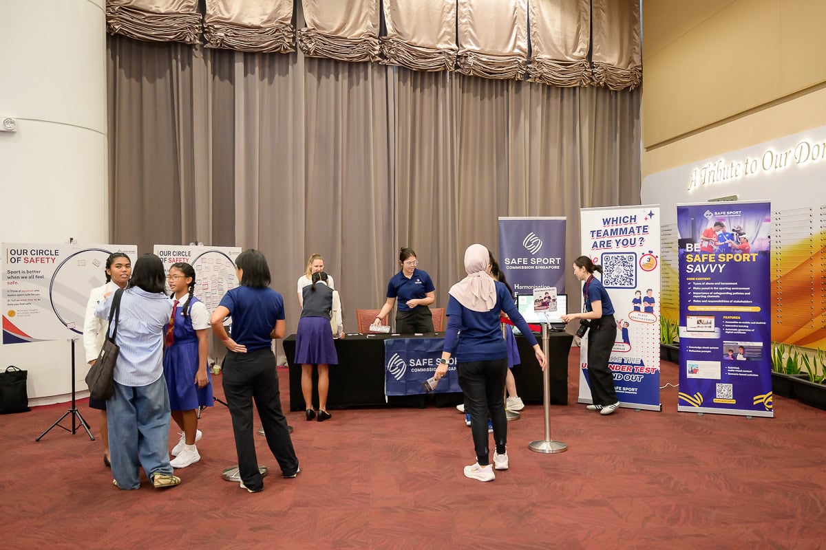 Attendees visiting the Safe Sport educational booth during a scholarship award ceremony in Singapore.